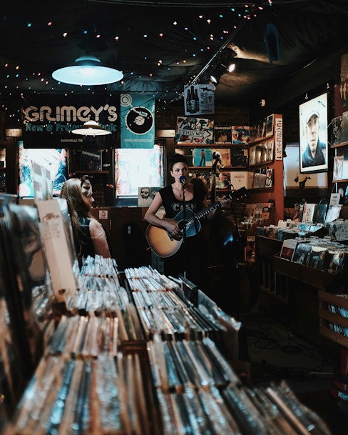 Woman performing live acoustic guitar performance in record store.